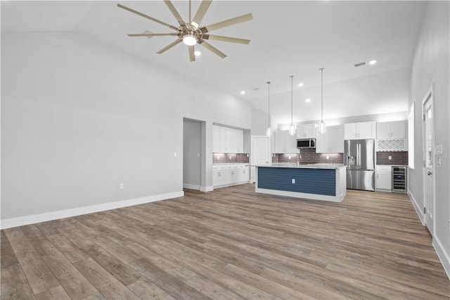 kitchen featuring stainless steel appliances, pendant lighting, high vaulted ceiling, white cabinets, and wine cooler