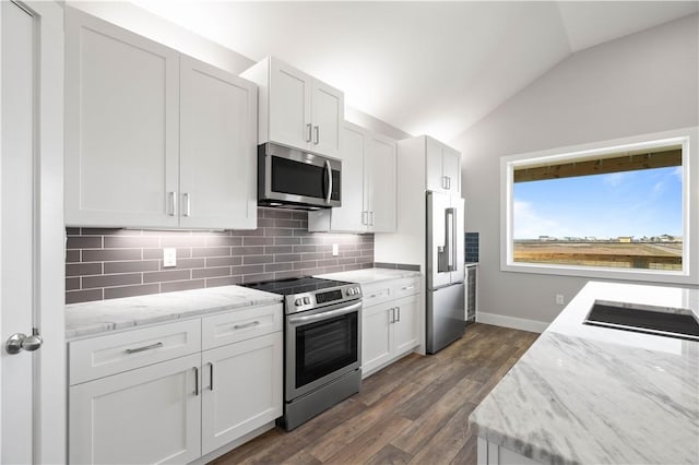 kitchen with light stone countertops, appliances with stainless steel finishes, tasteful backsplash, vaulted ceiling, and white cabinetry