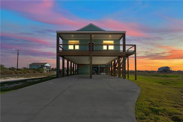 view of front of home featuring a lawn, a balcony, and a carport