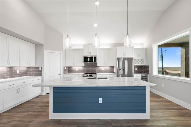 kitchen with hanging light fixtures, white cabinetry, a kitchen island with sink, and appliances with stainless steel finishes