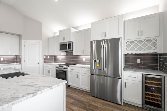 kitchen featuring white cabinetry, beverage cooler, stainless steel appliances, backsplash, and lofted ceiling