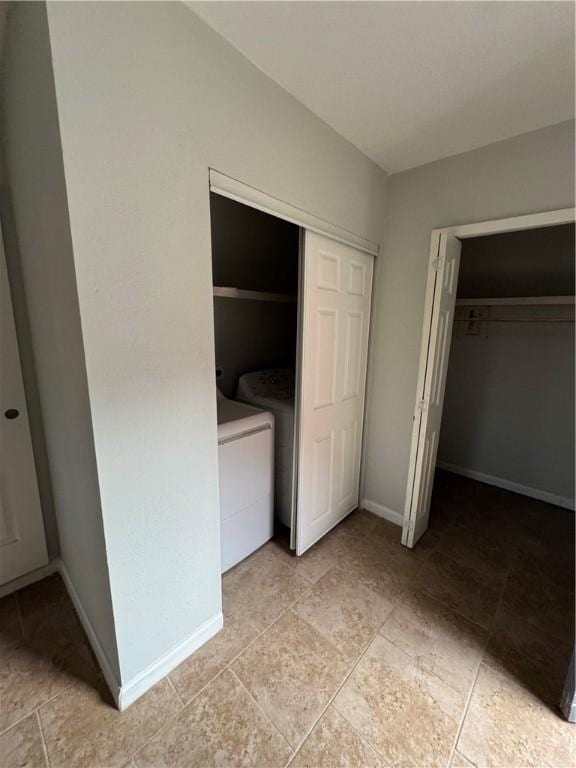 unfurnished bedroom with washer and dryer, baseboards, and a closet