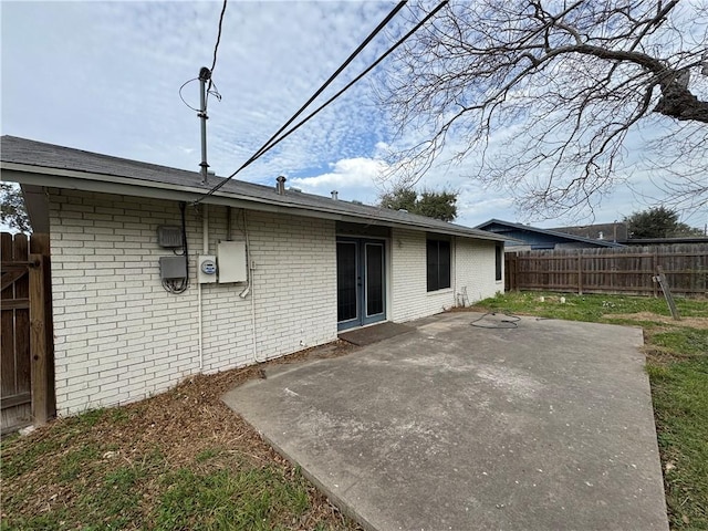 rear view of property featuring fence, brick siding, and a patio area