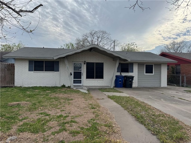 ranch-style home with brick siding, a front lawn, and fence