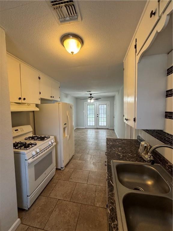 kitchen with visible vents, under cabinet range hood, a sink, white cabinetry, and white gas range