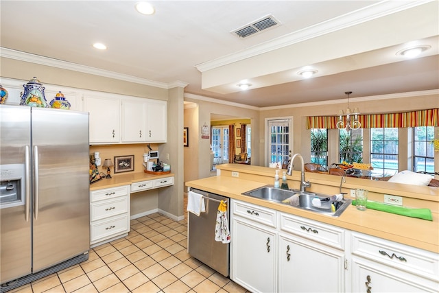 kitchen with stainless steel appliances, white cabinetry, sink, hanging light fixtures, and crown molding