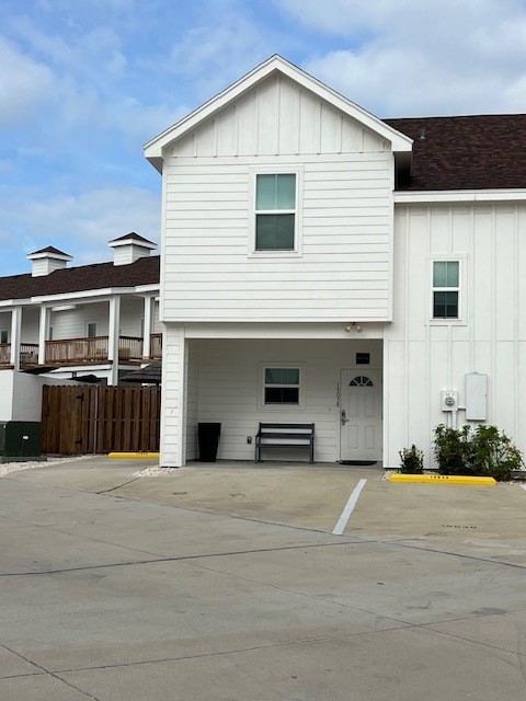 view of front of home with uncovered parking, fence, and board and batten siding