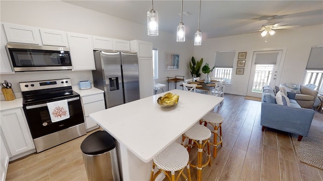 kitchen featuring stainless steel appliances, light wood-type flooring, open floor plan, and white cabinetry