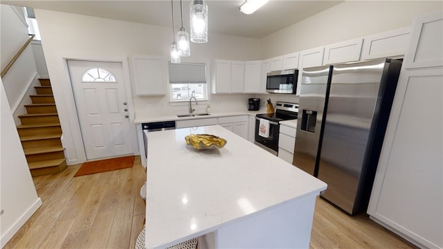 kitchen with white cabinetry, light wood-style flooring, appliances with stainless steel finishes, and a sink