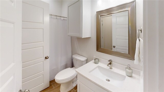 bathroom with toilet, wood finished floors, and vanity