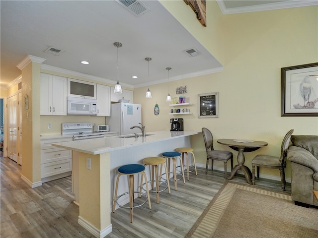 kitchen featuring hanging light fixtures, white appliances, a kitchen bar, and white cabinetry