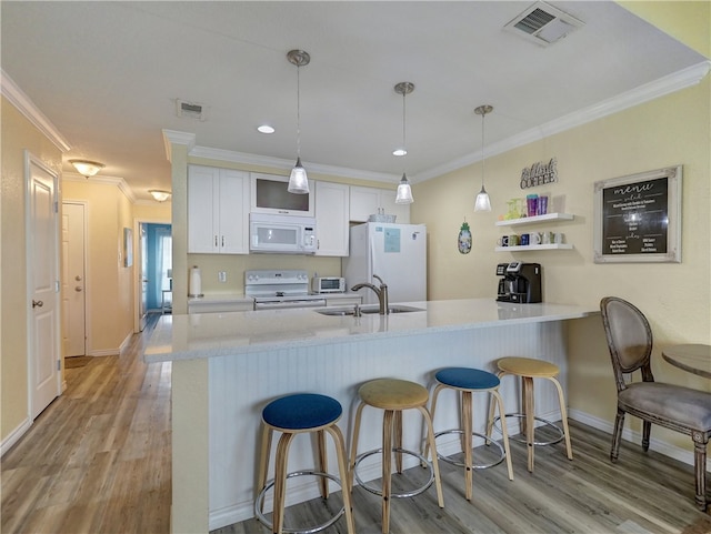 kitchen featuring ornamental molding, white cabinetry, kitchen peninsula, light hardwood / wood-style floors, and white appliances