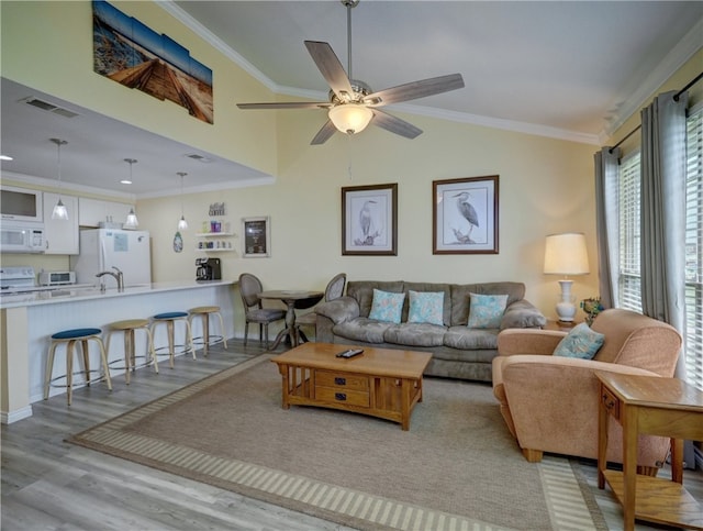 living room with light hardwood / wood-style floors, ceiling fan, and ornamental molding