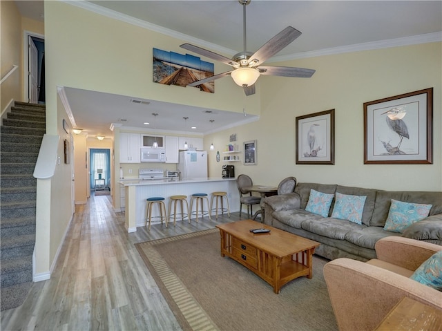 living room featuring ceiling fan, light hardwood / wood-style flooring, and crown molding