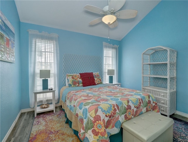 bedroom featuring hardwood / wood-style flooring, ceiling fan, multiple windows, and lofted ceiling