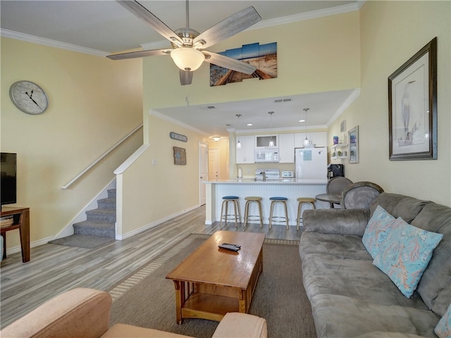 living room with light hardwood / wood-style floors, ceiling fan, and crown molding