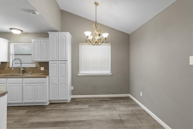 2718 Wind Rock Dr, Corpus Christi, TX 78410 - kitchen featuring a sink, white cabinetry, a chandelier, vaulted ceiling, and hanging light fixtures