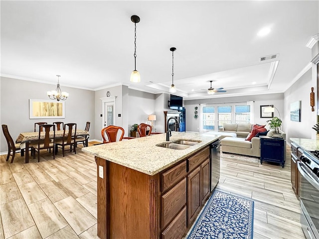 kitchen with sink, stainless steel appliances, a raised ceiling, a kitchen island with sink, and ceiling fan with notable chandelier