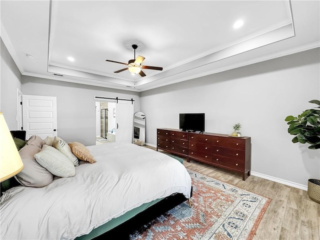 bedroom featuring a raised ceiling, a barn door, ceiling fan, and ornamental molding