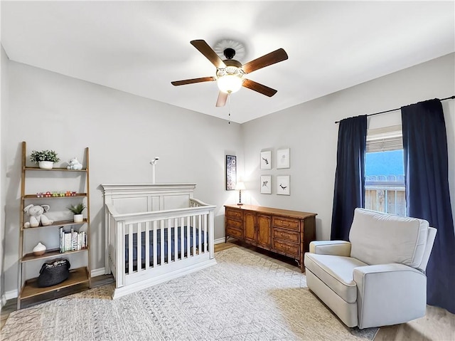 bedroom with ceiling fan and a nursery area