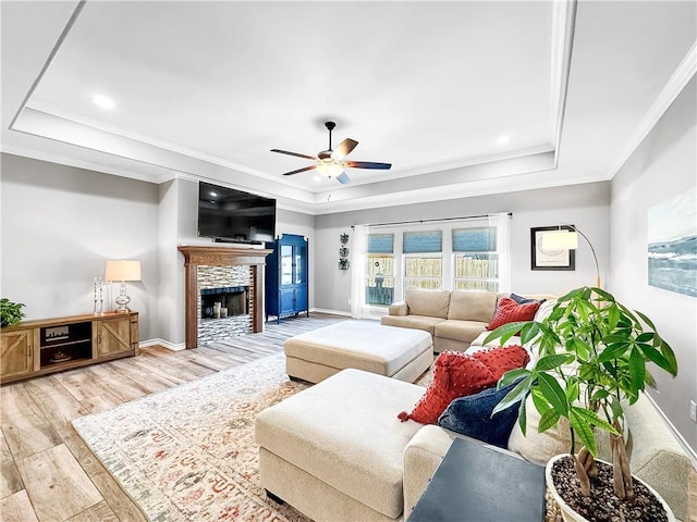 living room featuring a tray ceiling, ceiling fan, light hardwood / wood-style floors, and ornamental molding