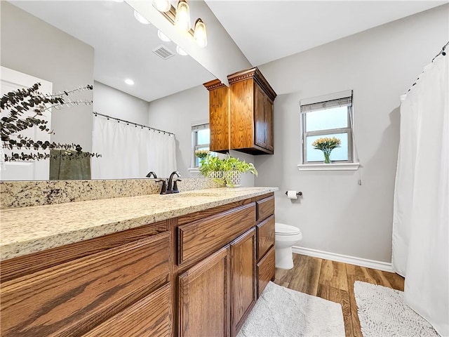 bathroom featuring plenty of natural light, vanity, wood-type flooring, and toilet