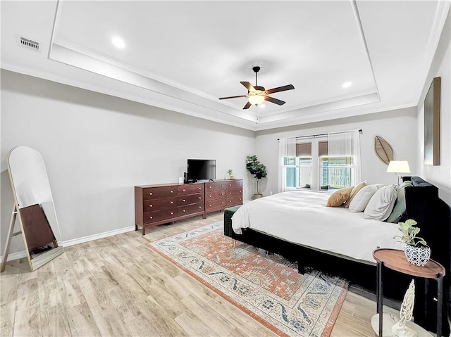 bedroom with wood-type flooring, a raised ceiling, ceiling fan, and ornamental molding