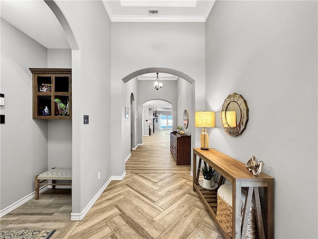 hall featuring a notable chandelier, parquet flooring, and crown molding