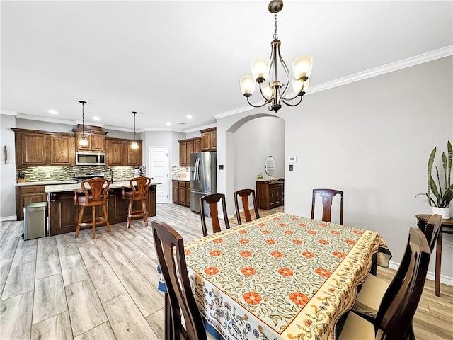 dining area with crown molding, a chandelier, and light wood-type flooring