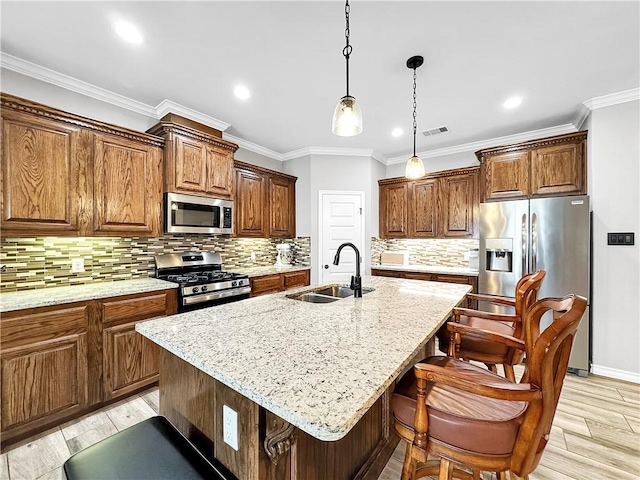 kitchen featuring backsplash, stainless steel appliances, a kitchen island with sink, and sink