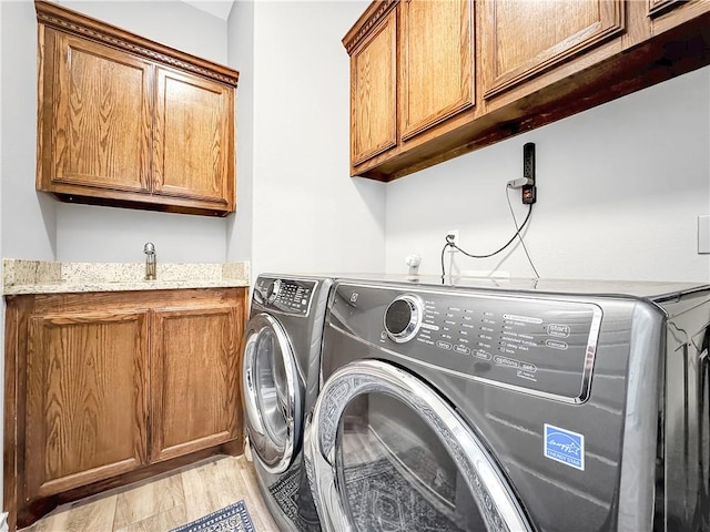 laundry room with separate washer and dryer, sink, cabinets, and light wood-type flooring