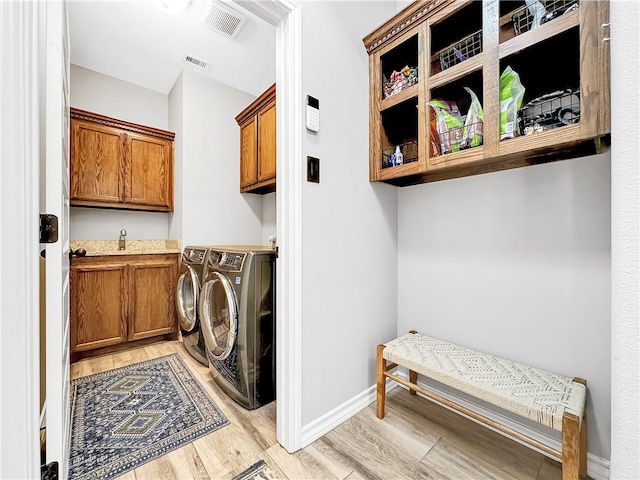 washroom featuring cabinets, light wood-type flooring, and washing machine and clothes dryer