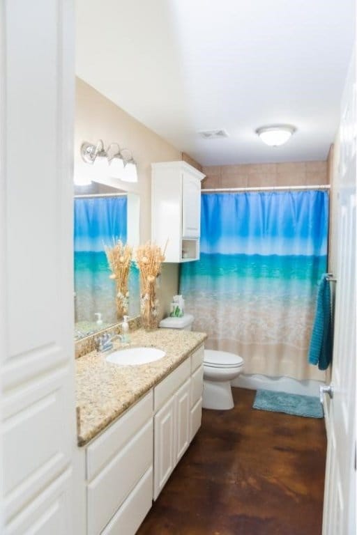 bathroom with concrete flooring, vanity, and toilet