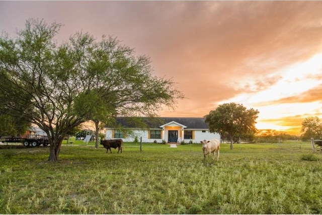 yard at dusk featuring a rural view