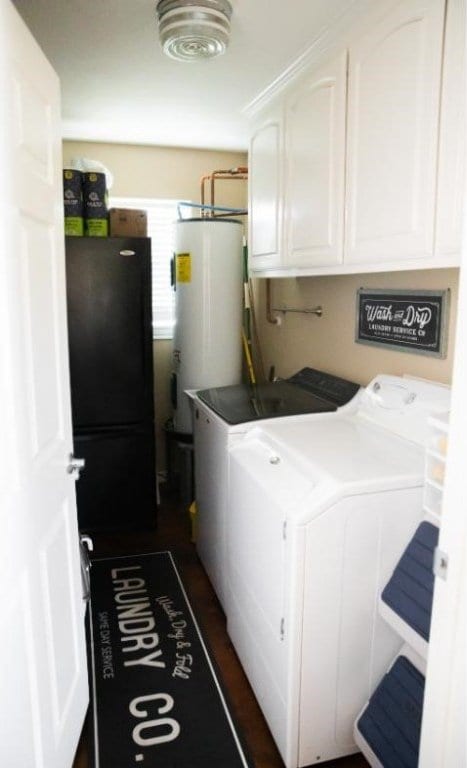 laundry area with washing machine and clothes dryer, water heater, and cabinets