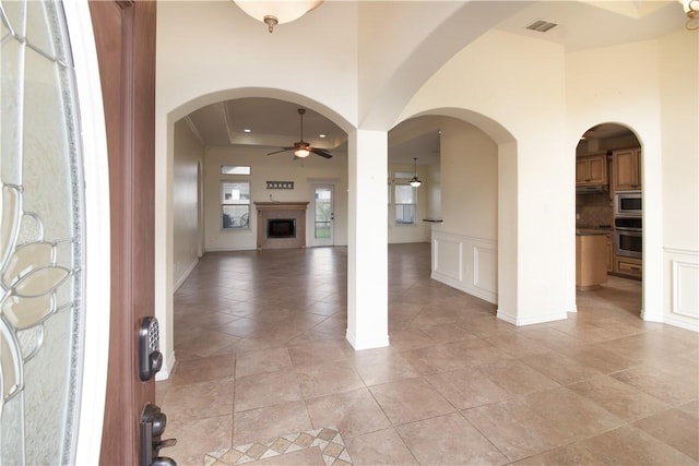 6825 Old Square Dr, Corpus Christi, TX 78414 - entrance foyer featuring ceiling fan, a fireplace, light tile patterned floors, and arched walkways
