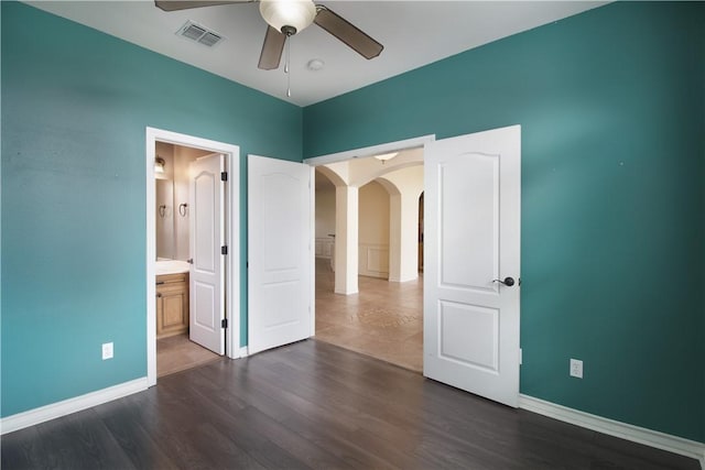 6825 Old Square Dr, Corpus Christi, TX 78414 - unfurnished bedroom with arched walkways, dark wood finished floors, connected bathroom, and a ceiling fan