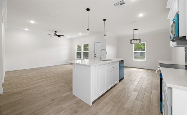 kitchen featuring an island with sink, sink, white cabinets, hanging light fixtures, and stainless steel appliances