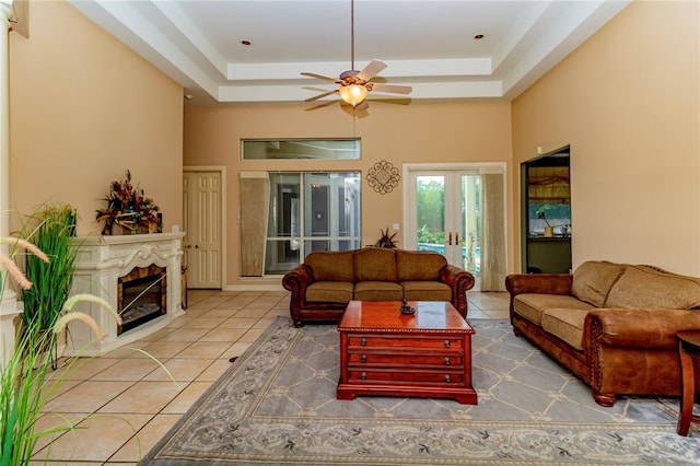 7906 Valtourmanche Dr, Corpus Christi, TX 78414 - tiled living area featuring a ceiling fan, a tray ceiling, a glass covered fireplace, and french doors