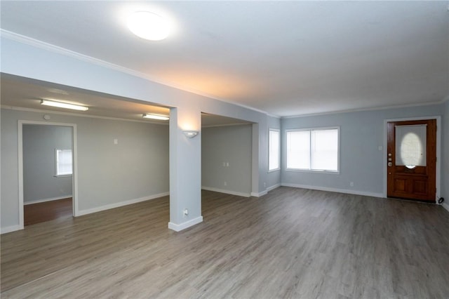 unfurnished living room featuring wood-type flooring and crown molding