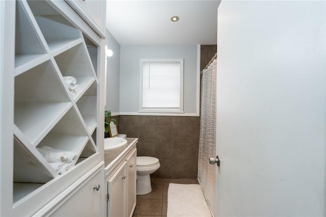 bathroom featuring tile patterned floors, vanity, toilet, and tile walls