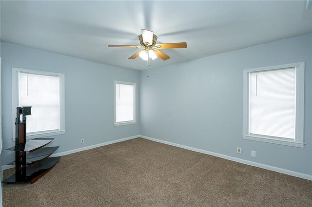 carpeted spare room featuring a wealth of natural light and ceiling fan