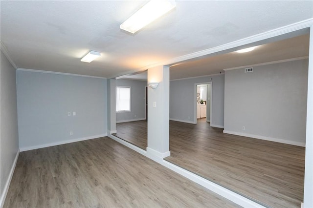 empty room featuring wood-type flooring and ornamental molding