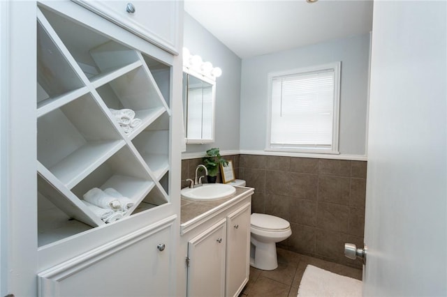 bathroom with tile patterned floors, vanity, tile walls, and toilet