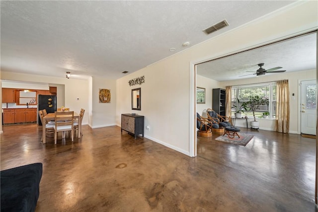 living room featuring visible vents, finished concrete flooring, baseboards, a textured ceiling, and a ceiling fan