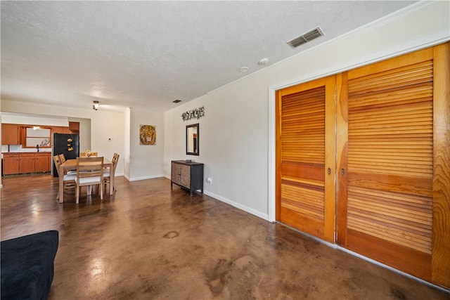 living room with visible vents, a textured ceiling, baseboards, and finished concrete floors