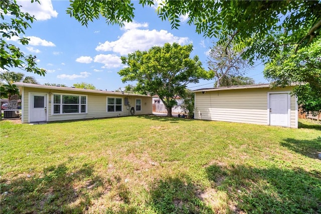 rear view of property with a lawn, central AC unit, and an outdoor structure