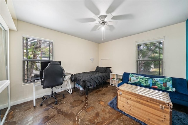 bedroom with a ceiling fan, baseboards, and finished concrete floors