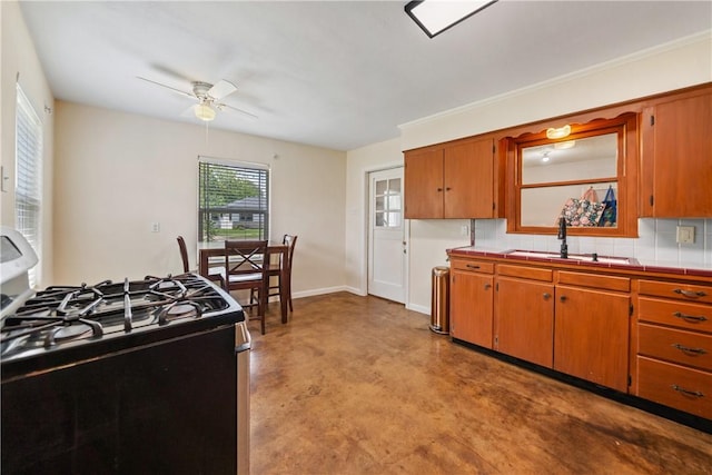 kitchen featuring decorative backsplash, ceiling fan, finished concrete floors, a sink, and range with gas stovetop