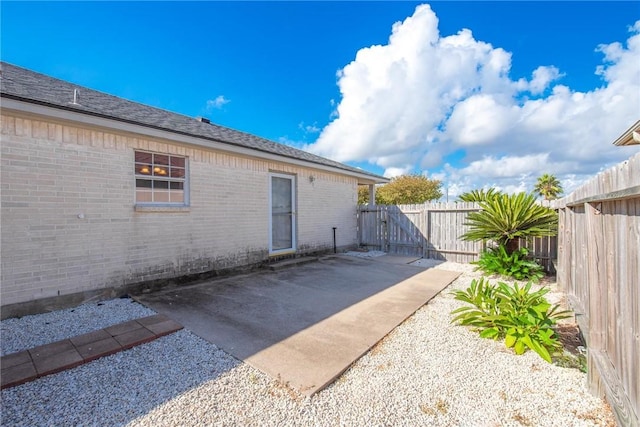 15522 Finistere St, Corpus Christi, TX 78418 - view of side of property with a fenced backyard, a patio, brick siding, and a gate